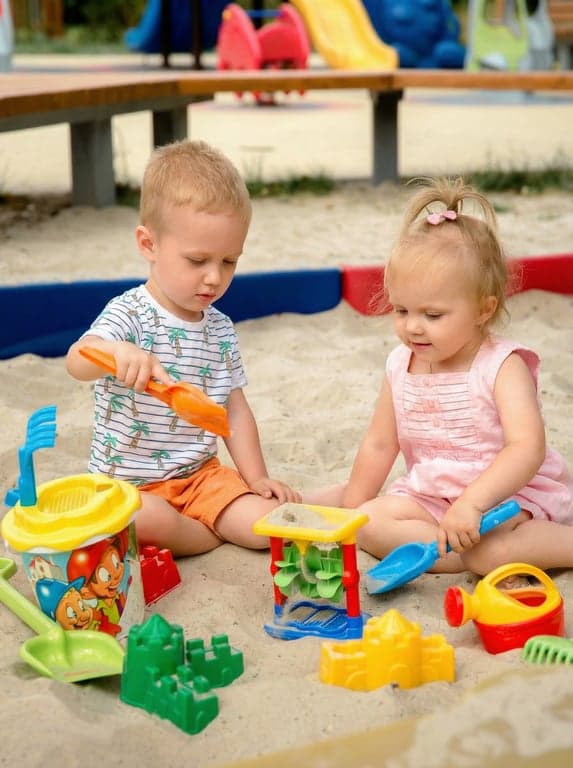 Two kids in the sandbox, ready to colour
